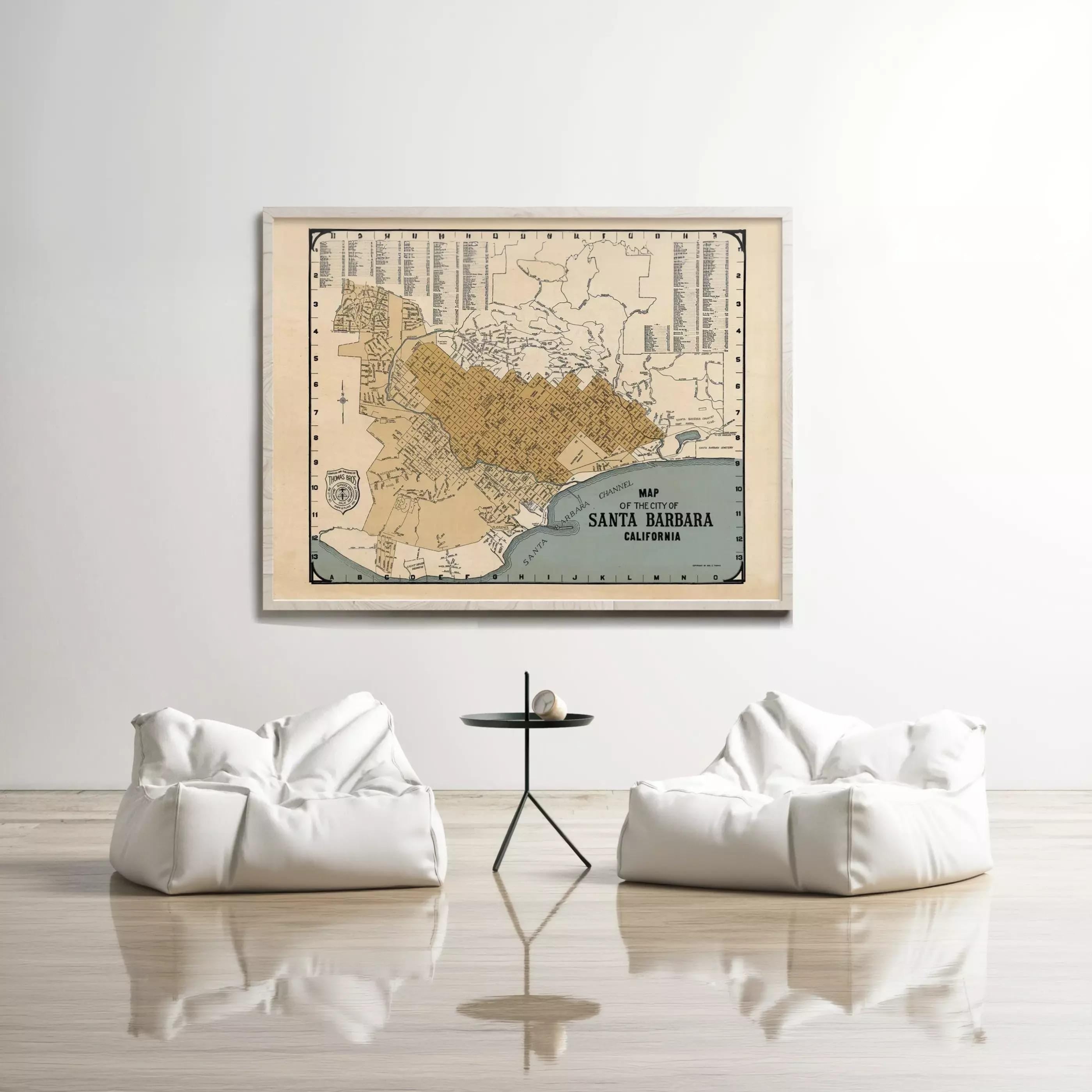 a large framed map of Santa Barbara, California, hanging on a white wall above a pair of white bean bag chairs and a small black table.