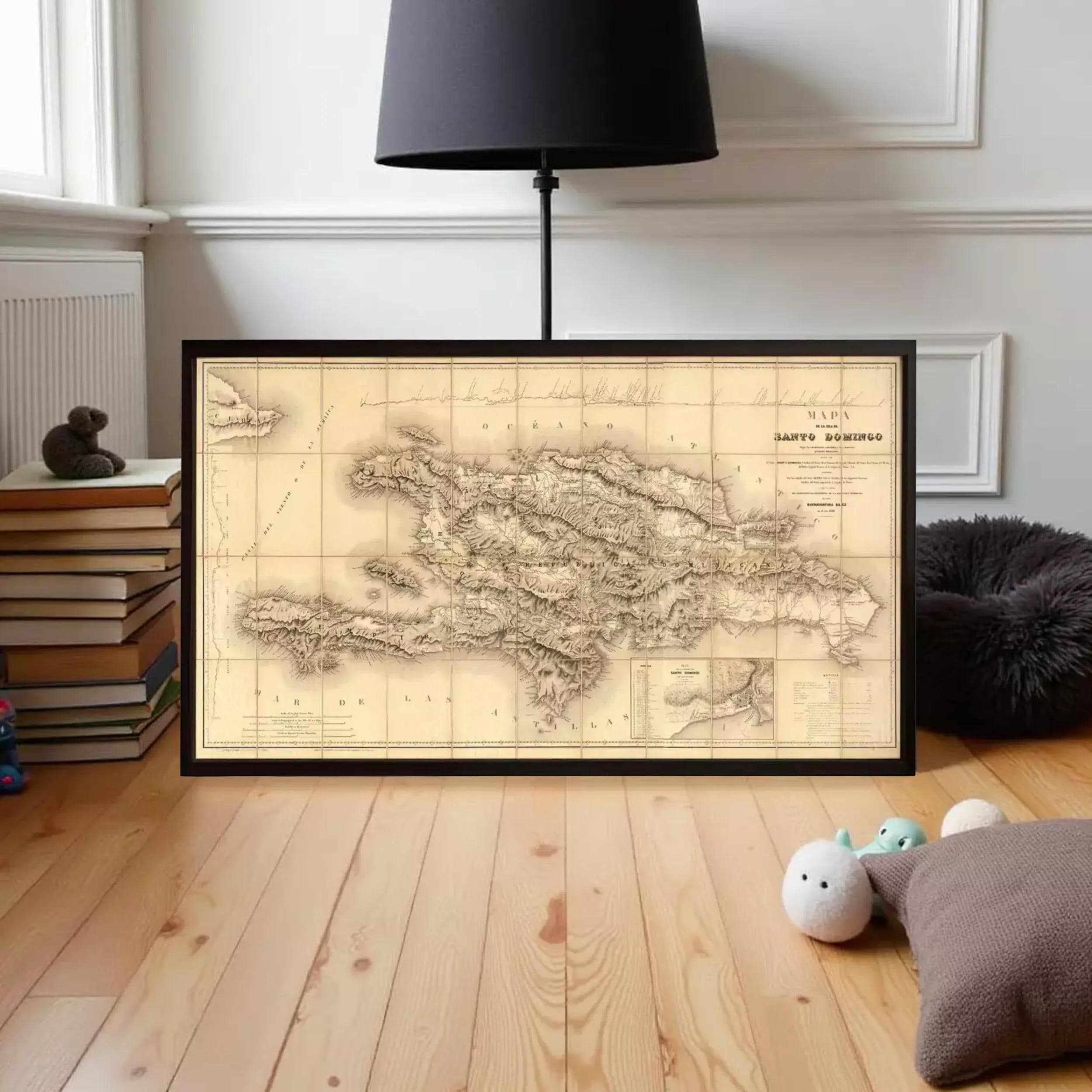 a framed map of the Dominican Republic on a wooden floor, with a lamp and some books in the background.