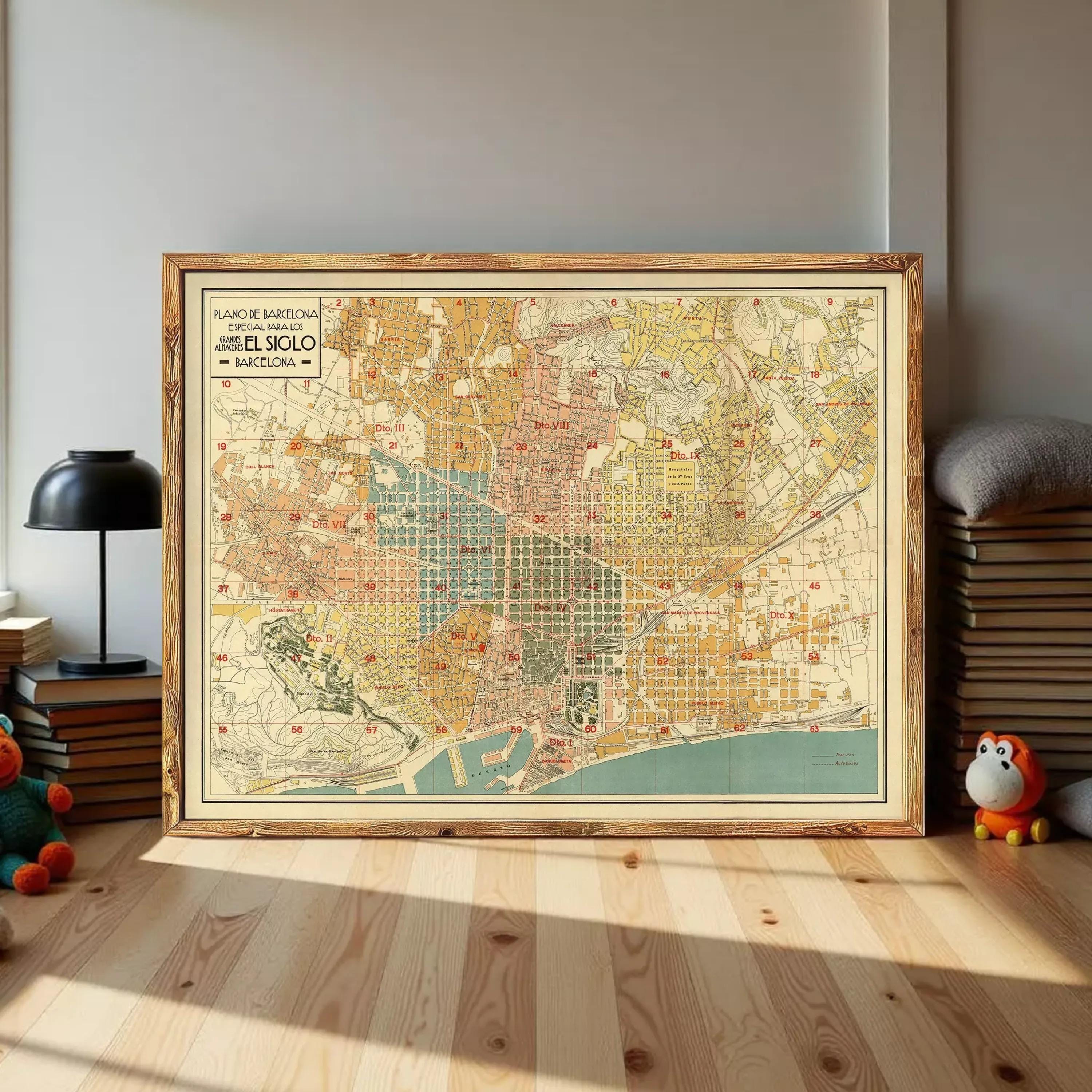 a large framed map of Barcelona, Spain, with a wooden frame and a vintage style. The map is displayed on a wooden floor, with a stack of books and a stuffed animal nearby.