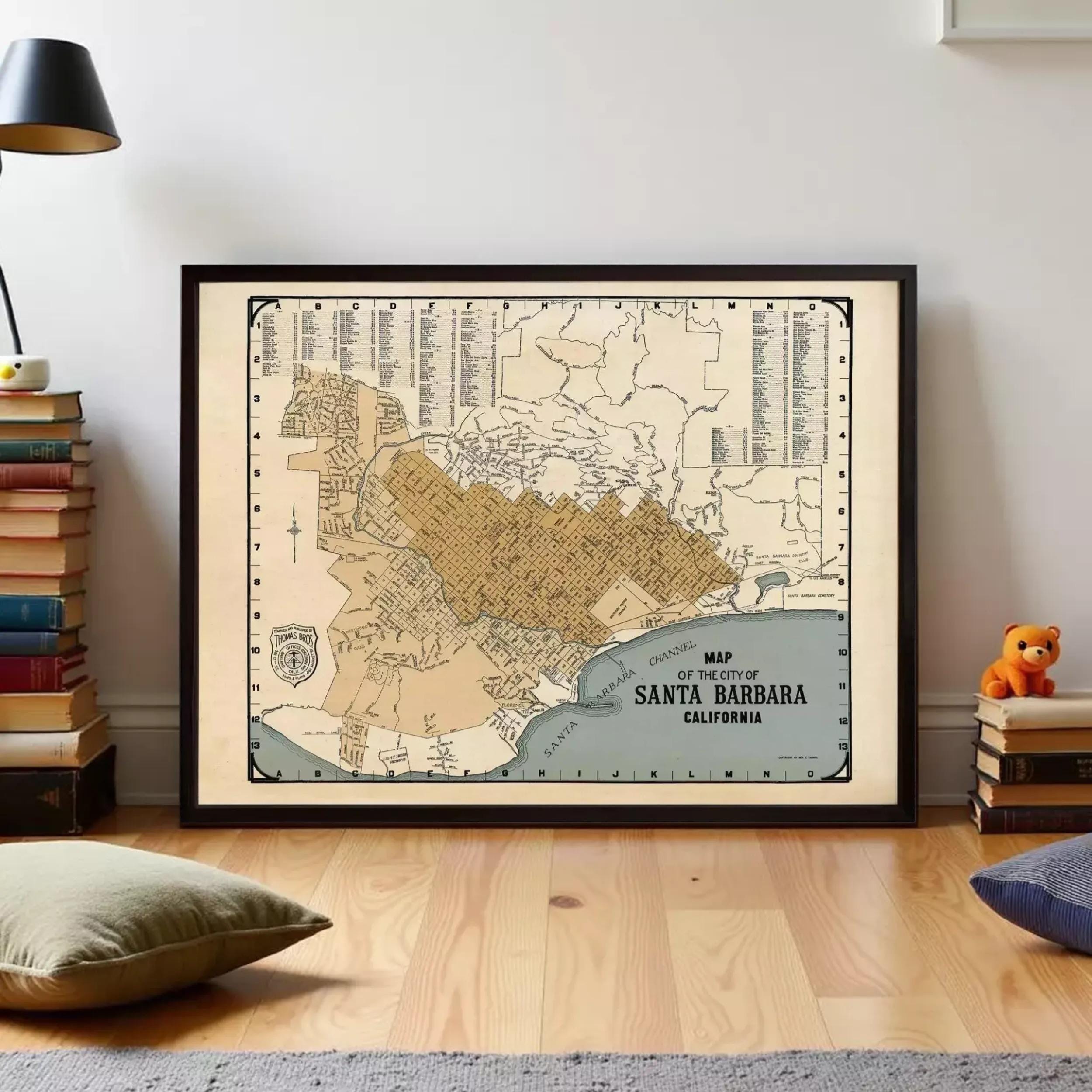 a framed map of Santa Barbara, California, with a teddy bear on a stack of books to the right side.