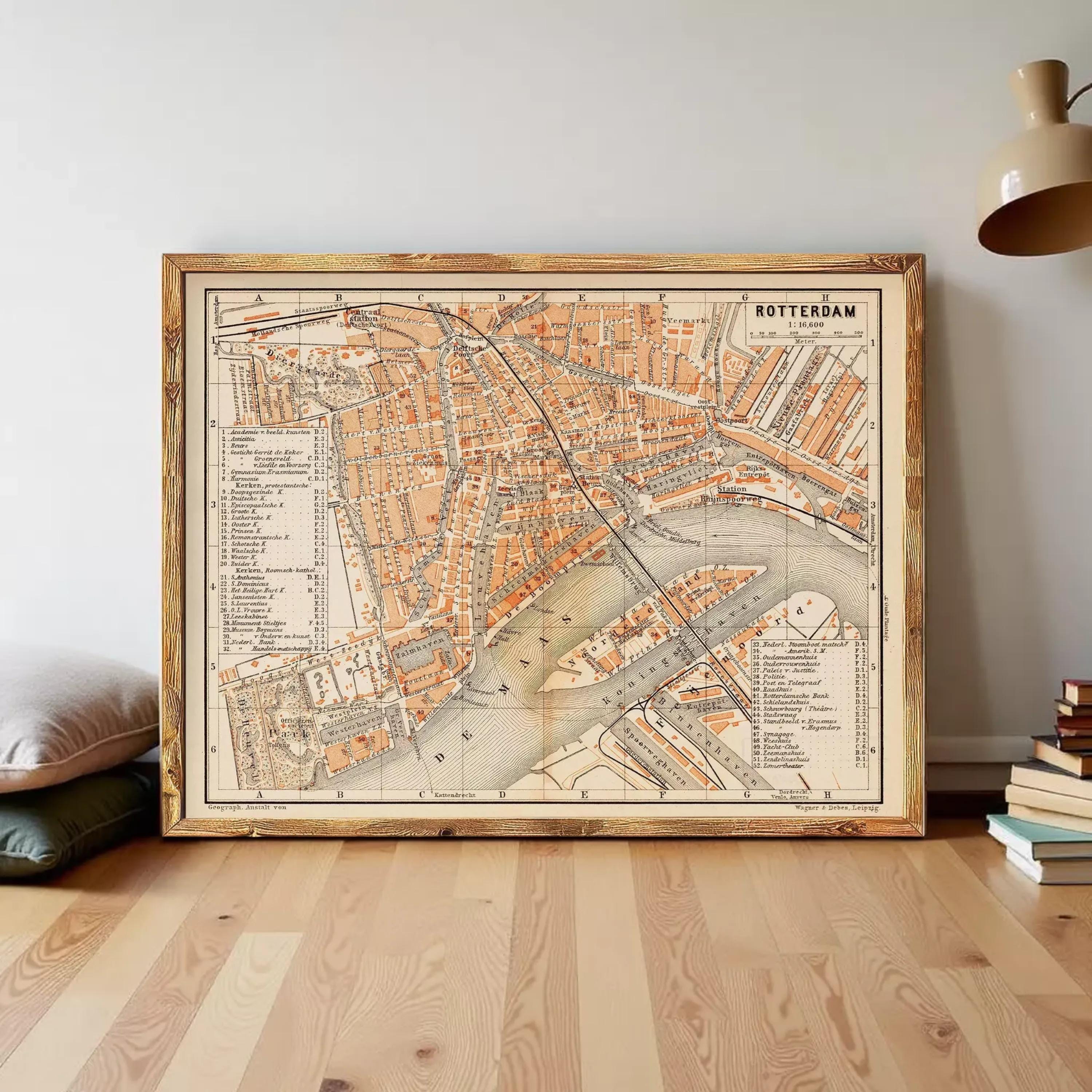 a large, framed map of Rotterdam, a city in the Netherlands. The map is displayed on a wooden floor, with a lamp and some books visible in the background.