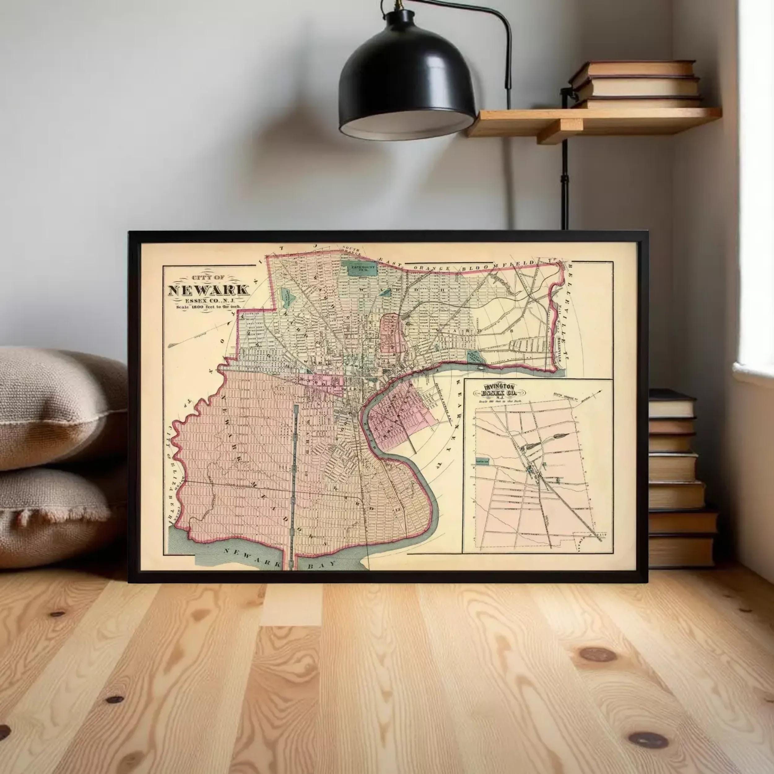 A framed map of New York City from 1873 is displayed on a wooden floor in a room with a bookshelf and a lamp.