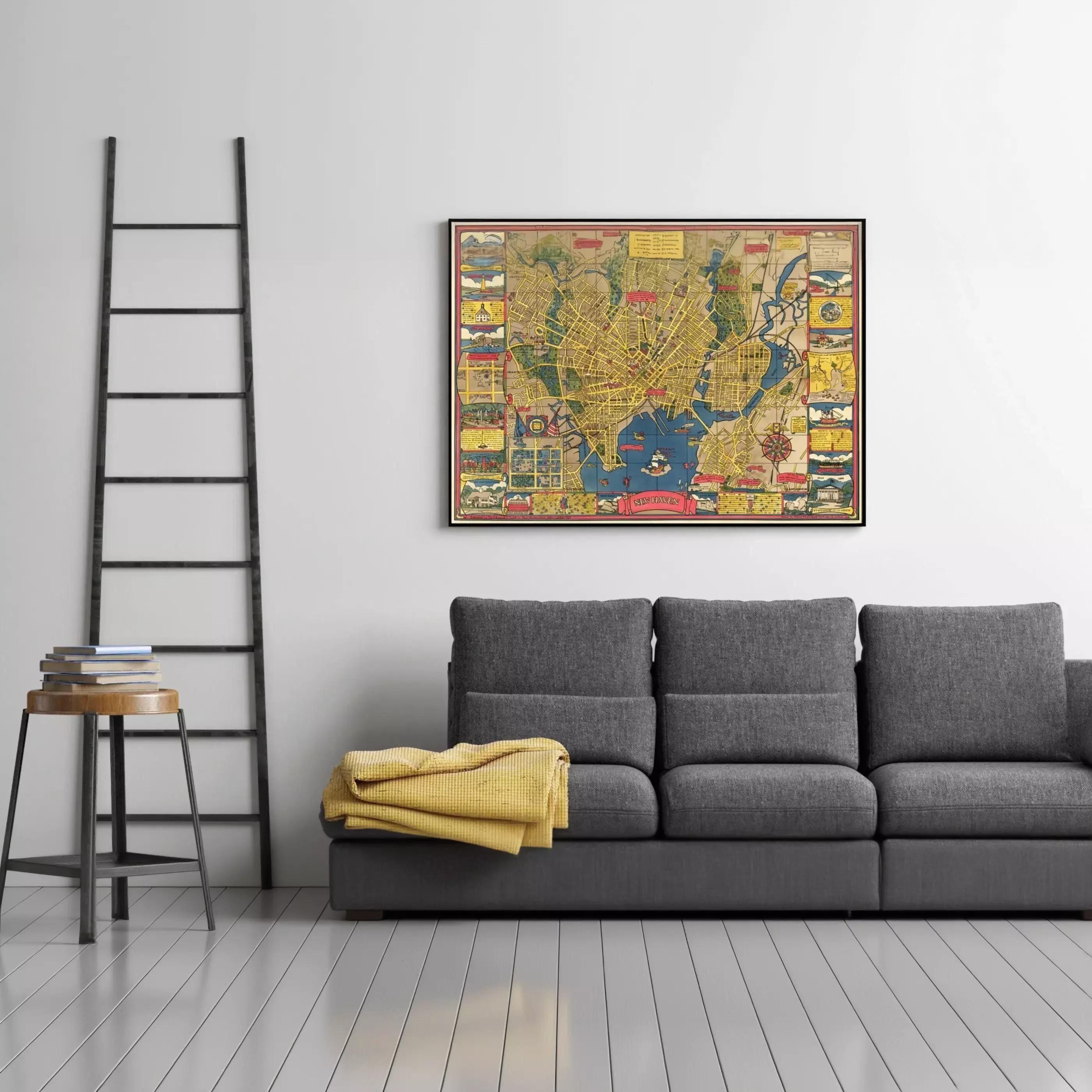 a gray couch with a yellow blanket on it, and a framed colorful map hanging on the wall above it. There is also a ladder in the room.