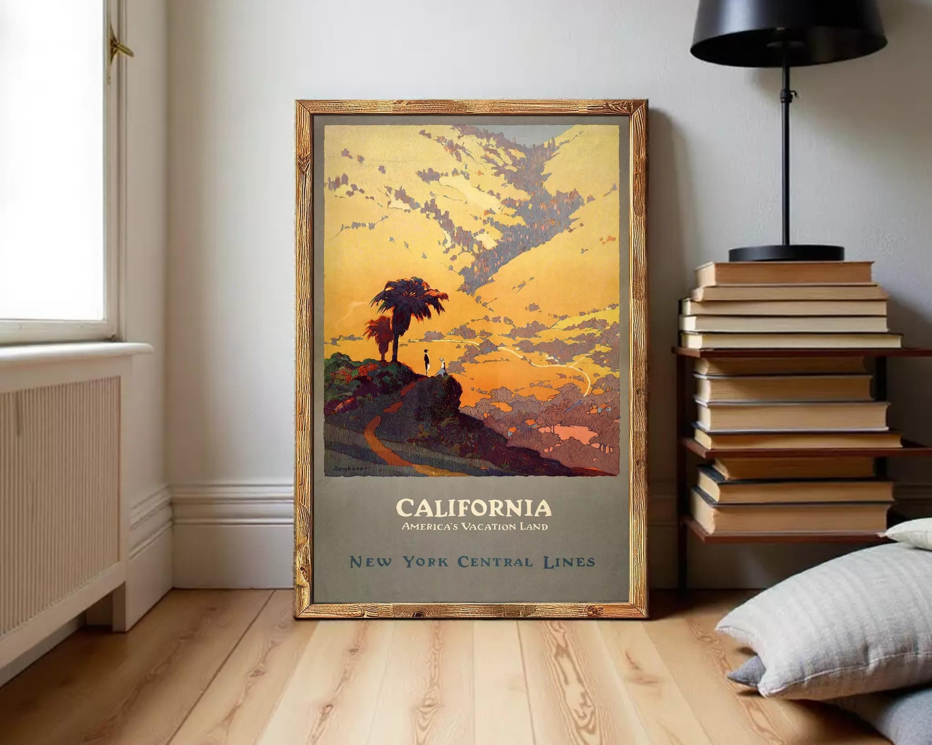 A framed vintage poster depicting a scenic landscape with a palm tree, mountains, and a sunset sky, advertising California as a vacation land.