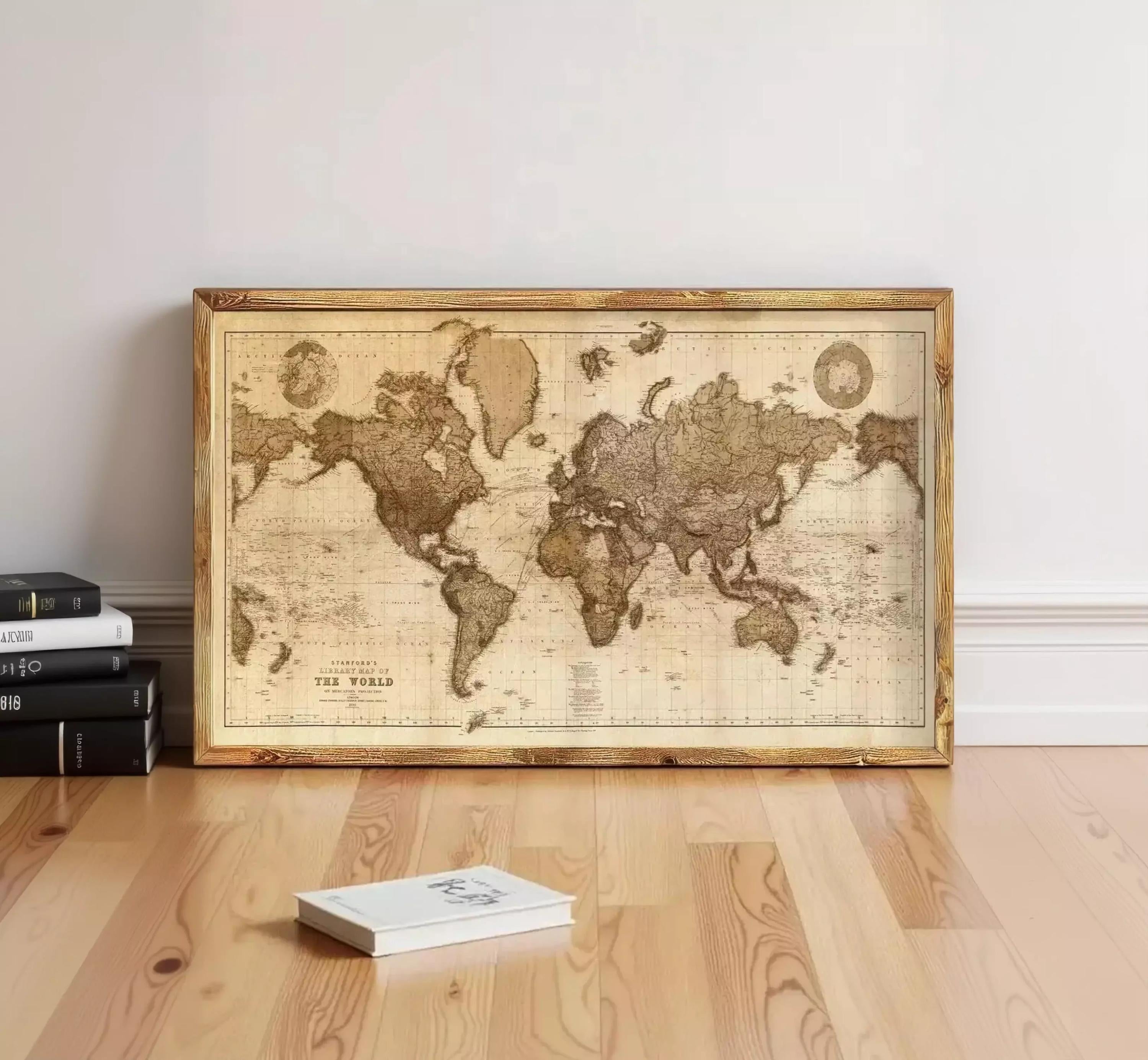 a large world map displayed on a wooden floor, with a stack of books and a book lying nearby.