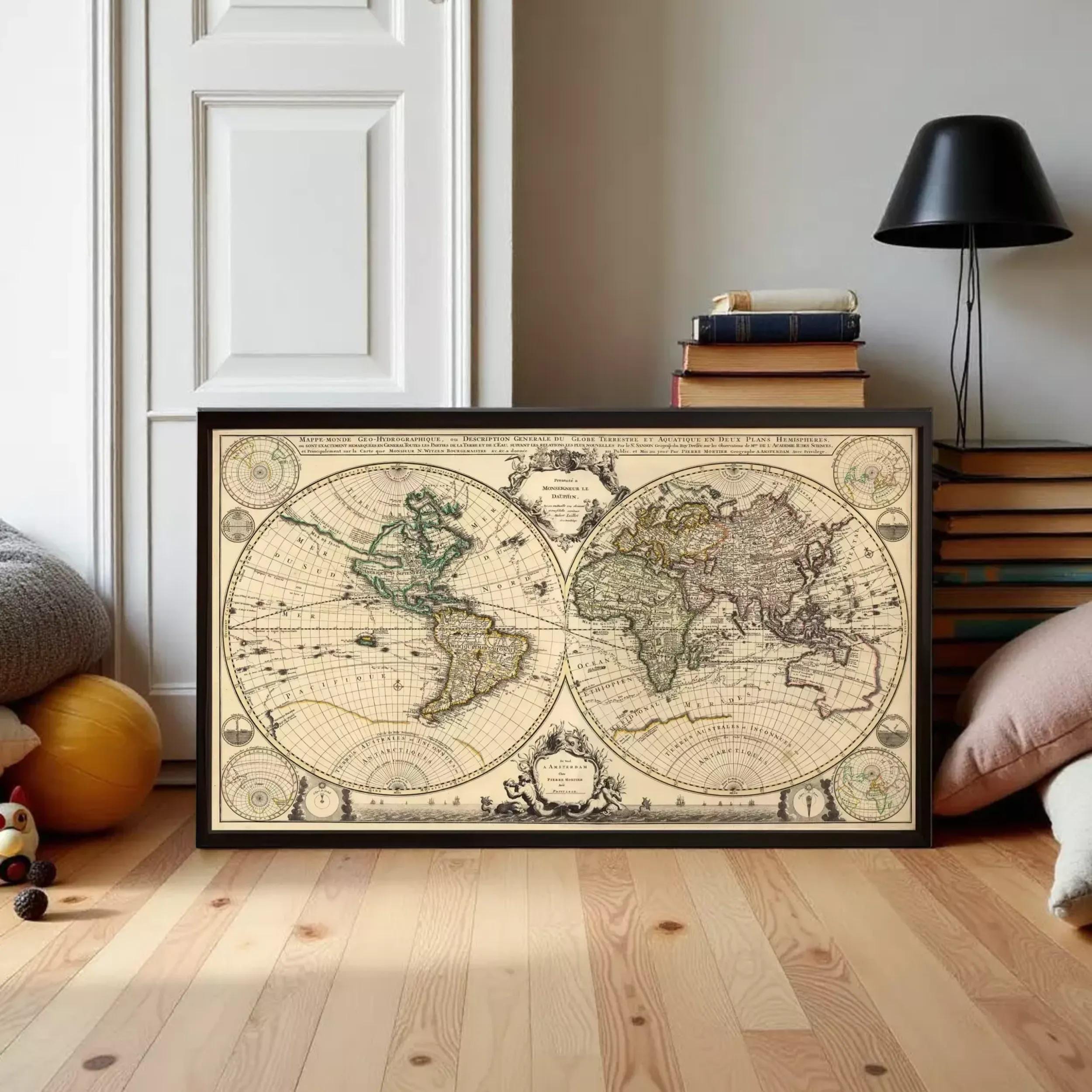 A framed antique world map is displayed on a wooden floor in a room with a white door and a lamp.