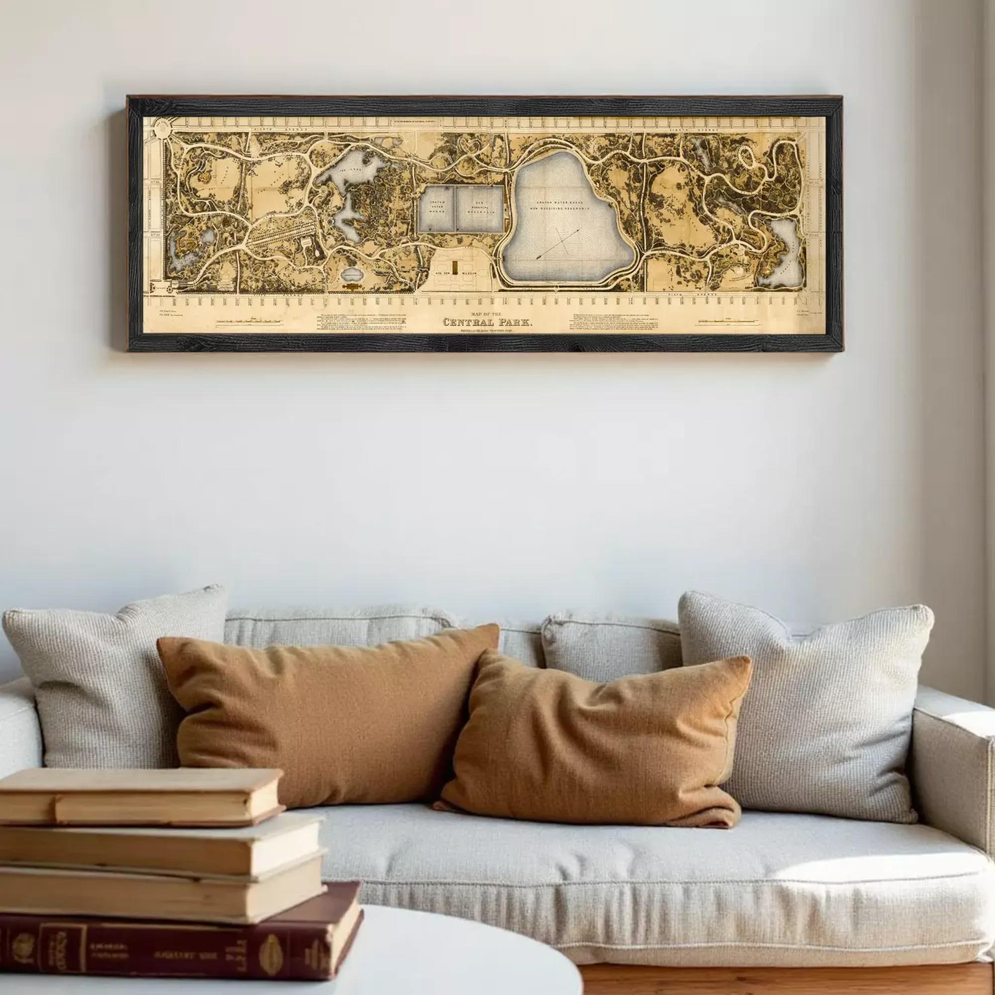 a framed map of Central Park hanging on a wall above a couch with pillows.