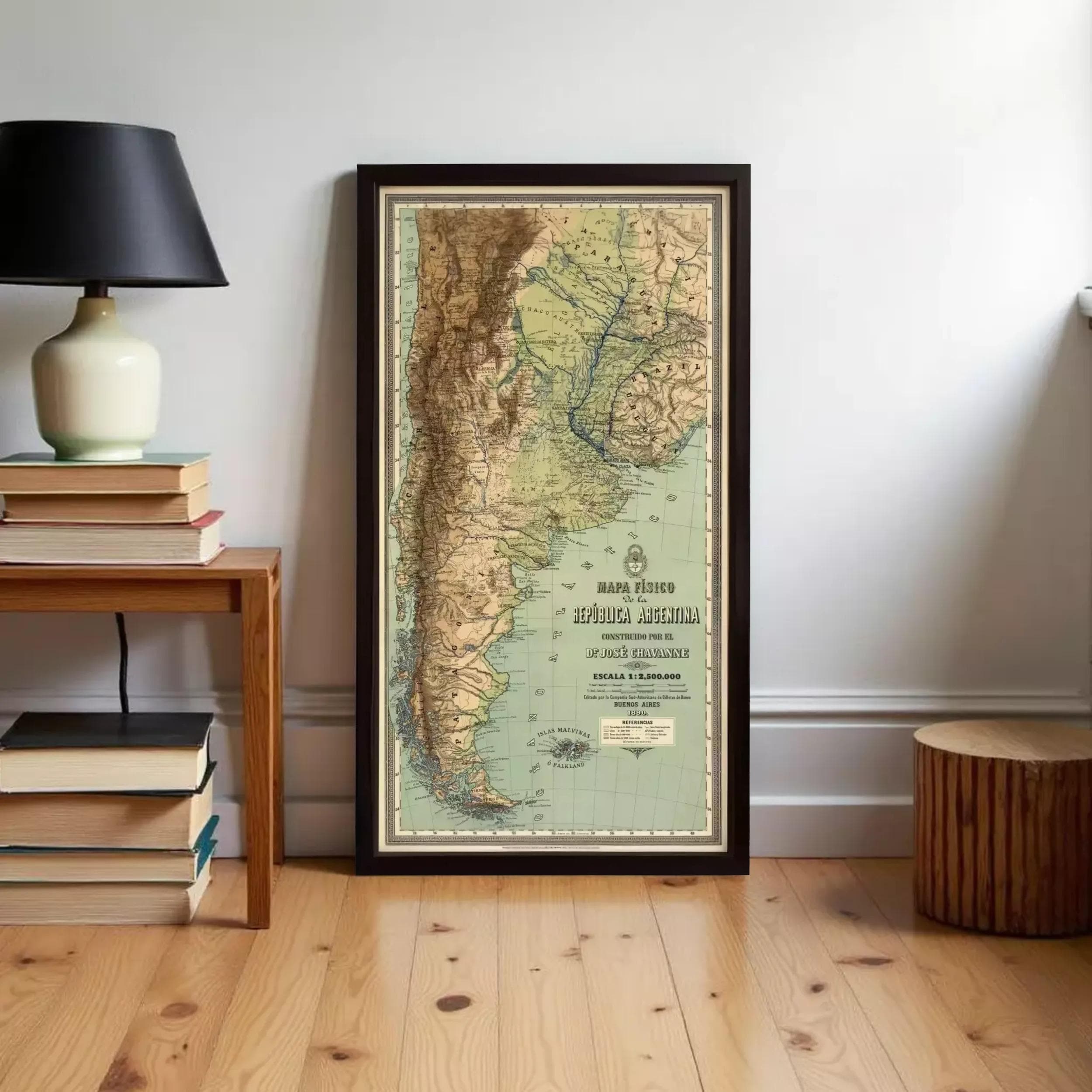 A framed map of South America, specifically Argentina, is displayed on a wall in a room with a wooden floor and a stack of books nearby.
