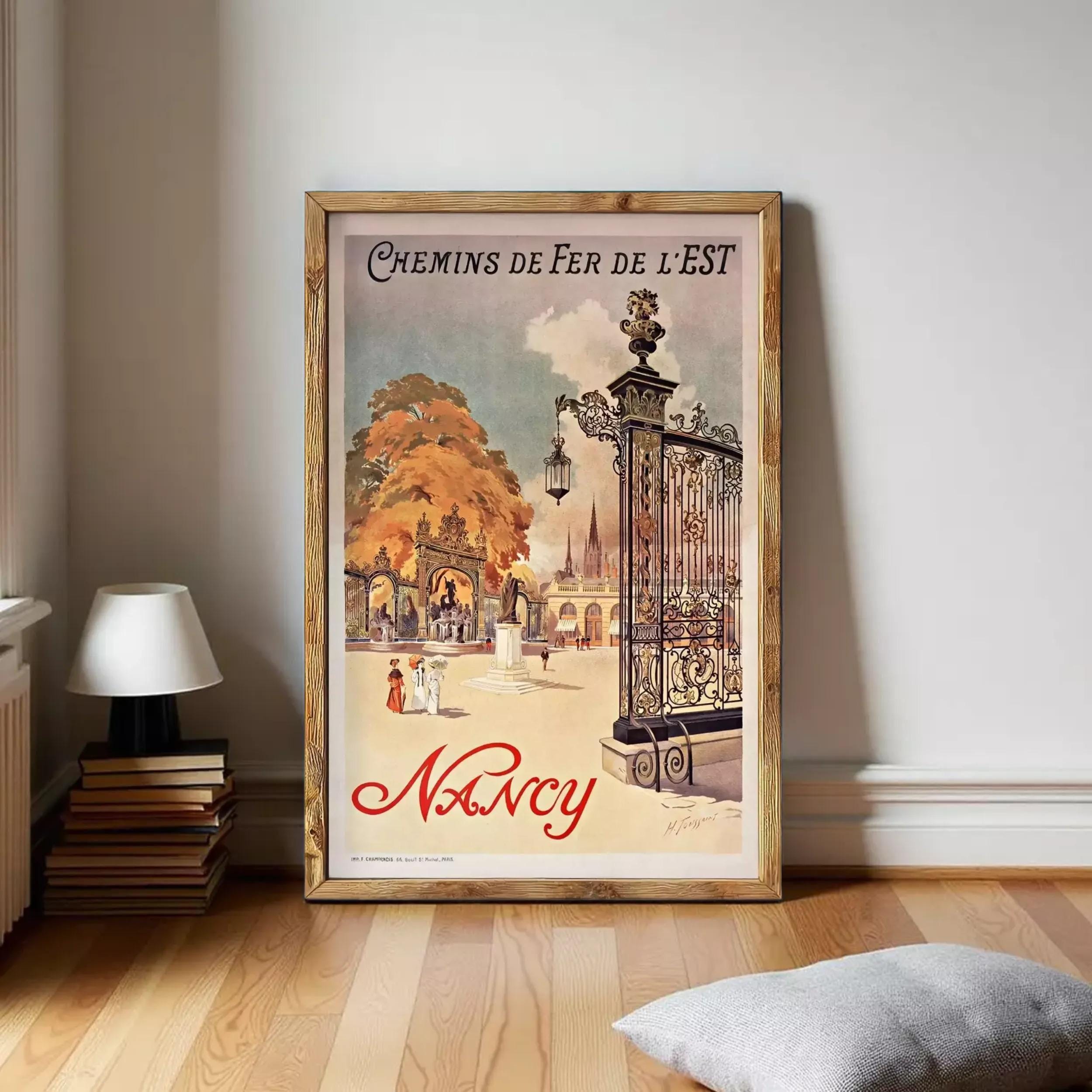 A framed vintage poster advertising Nancy, featuring an ornate gate and a scenic background with people and buildings.