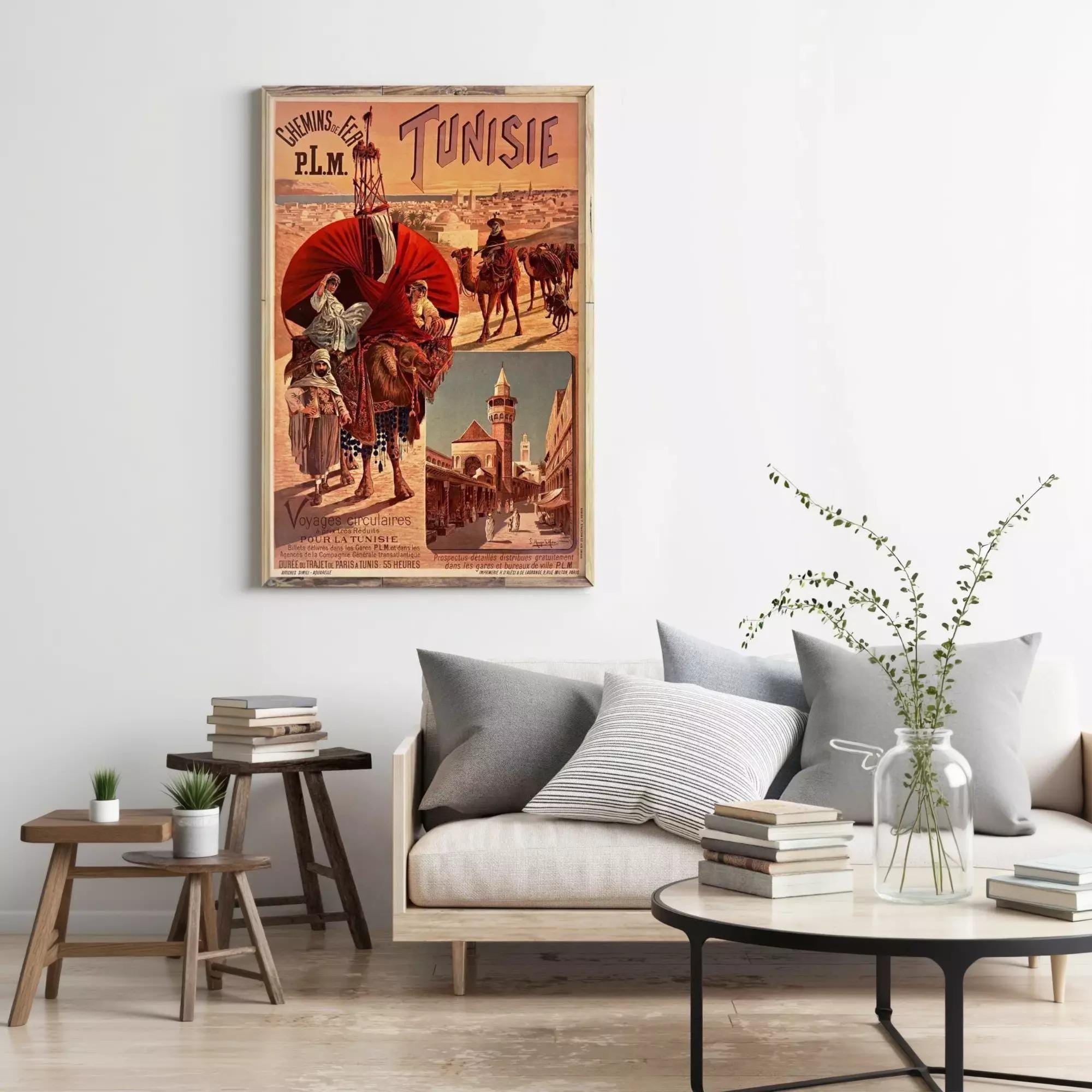 a vintage poster of a camel and a person in a desert setting, hanging on a wall above a couch and a coffee table in a living room.
